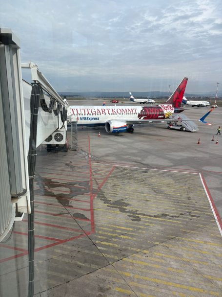 Flughafenansicht mit mehreren Flugzeugen und einem Gate im Vordergrund.